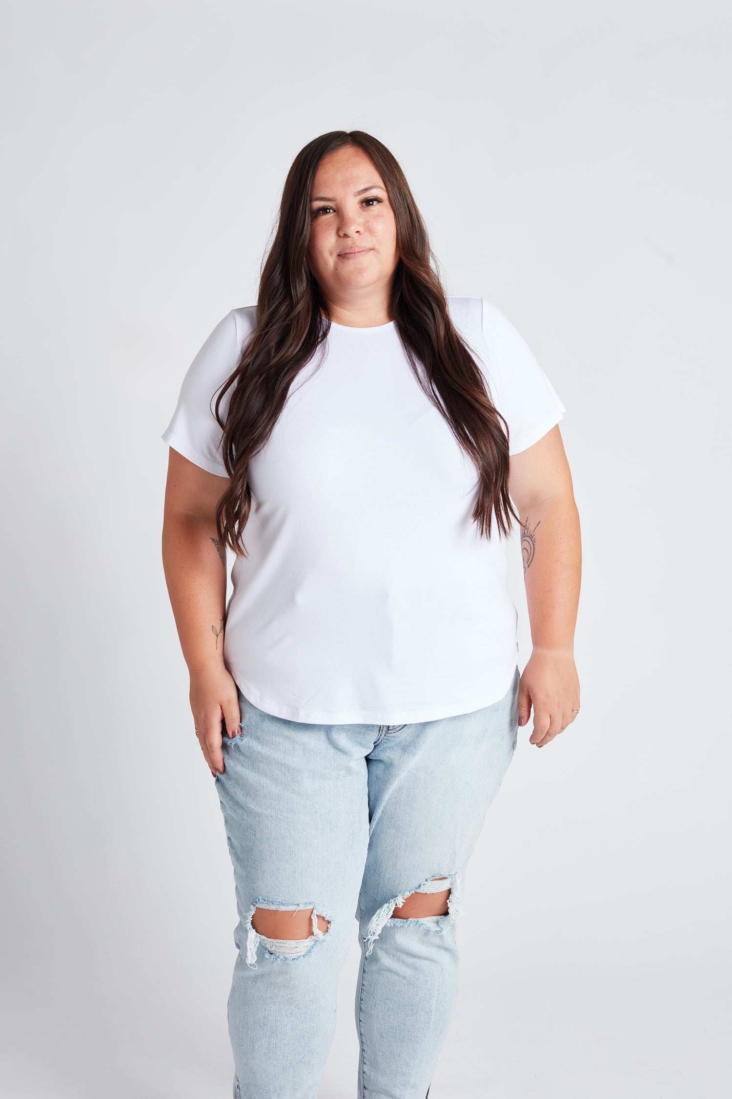 Woman wearing a white crew tshirt and jeans looking at the camera